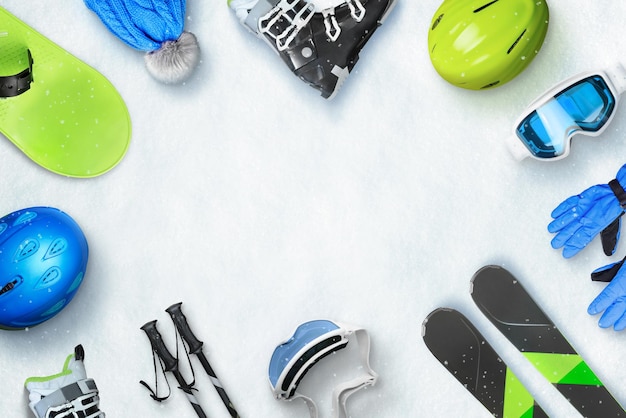 Winter ski sport accessories placed on snow with copy space in the middle for text or logo promotion Top view flat lay Winter ski vacation concept