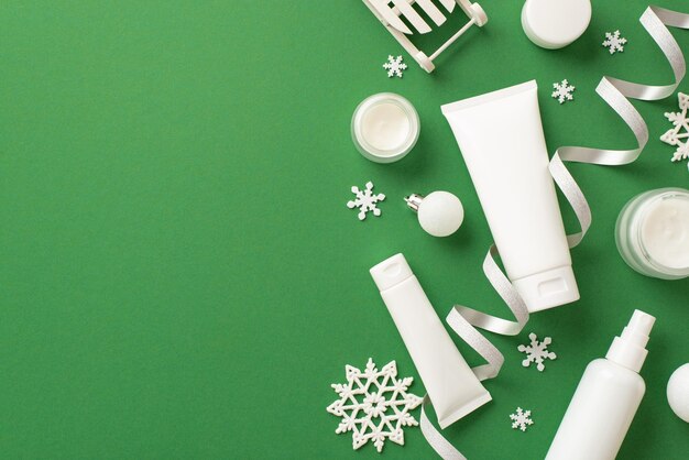 Winter skincare cosmetics concept top view photo of white tubes jars spray bottles baubles christmas ornaments serpentine and snowflakes on isolated green background with empty space