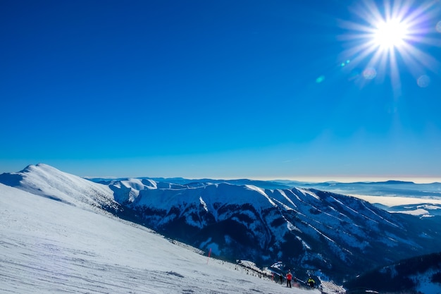 冬のスロバキア。スキーリゾートジャスナ。雪をかぶった山々とスキーヤーとスキースロープの頂上からの眺め