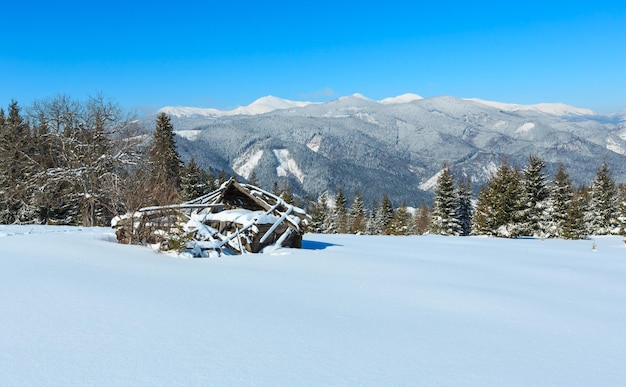 冬の雪に覆われたカルパティア山脈と古い廃墟の木造小屋ウクライナ