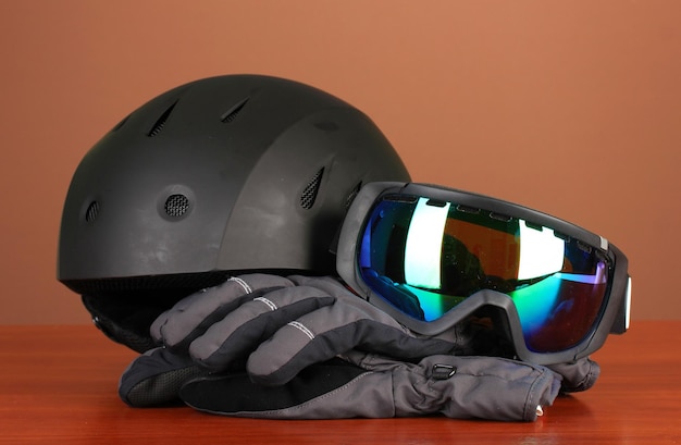 Winter sport glasses helmet and gloves on brown background