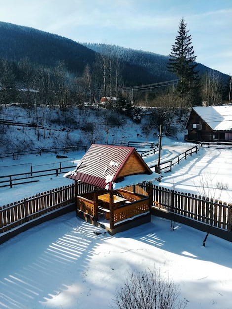 ウィンタースポーツスキーのコンセプト。山の中の雪の多い森の風景晴れた日の小さな家