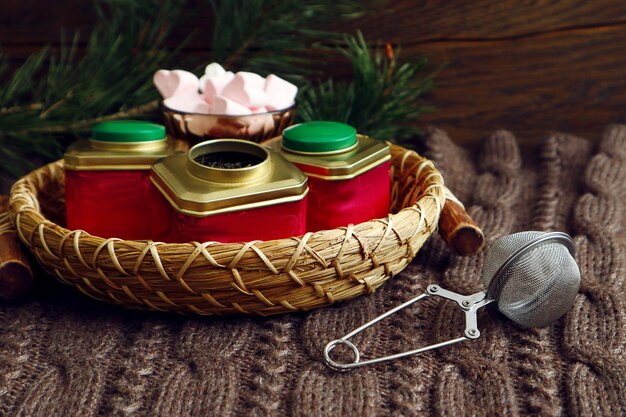 Winter still life multicolored boxes with tea a strainer air marshmallows in a vase a burning candle on a knitted product space for text closeup