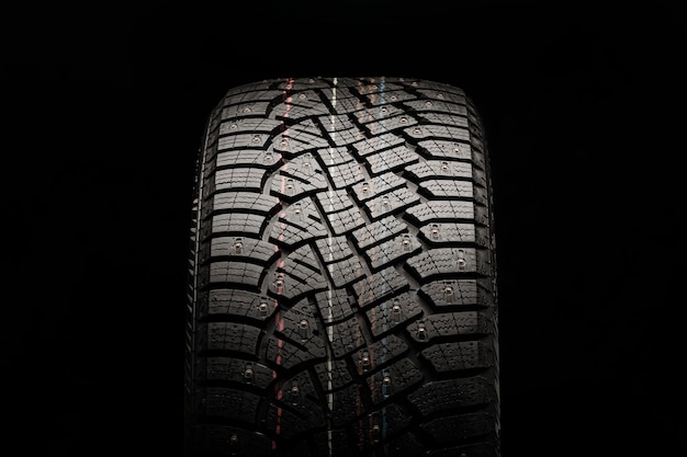 Winter studded tire, front view. close-up on a black background.