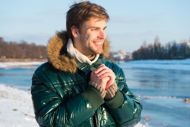 Winter stylish menswear. Winter outfit. Hipster winter fashion outfit. Guy wear jacket with hood on frosty winter day. Man bearded stand warm jacket snowy nature background. Wind resistant clothes.