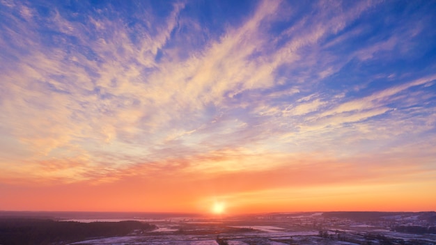 写真 冬の夕焼けの田舎の空の景色-地平線に沈む夕日と見事な夕焼けの空