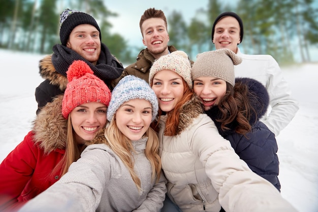 winter, technologie, vriendschap en mensenconcept - groep glimlachende mannen en vrouwen die selfie buitenshuis nemen