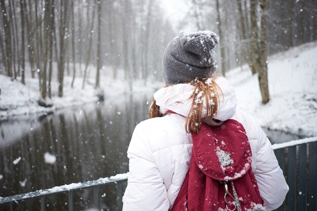 冬時間。初雪。降雪を楽しむ若い魅力的な陽気な女の子。