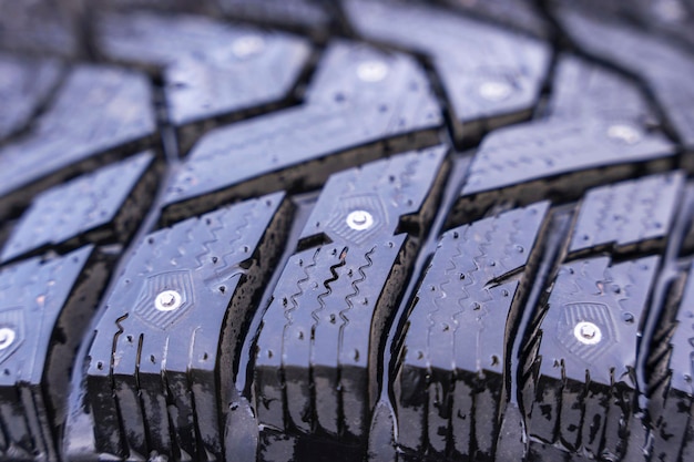 Winter tires with spikes on a black background closeup