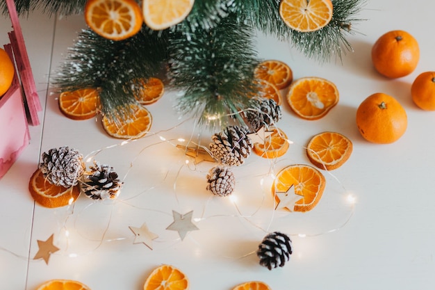 In winter, the tree is decorated with dried oranges outside, green branches against a blurred background, and yellow-gold bokeh. Festive decor in eco style. Merry Christmas.