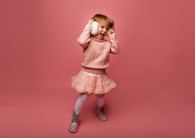 Winter vacation. Little girl listens to music in winter headphones. Girl in winter clothes.