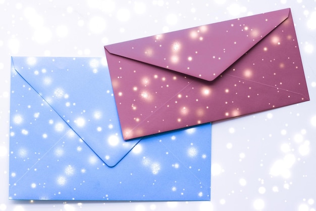Foto winter vakantie blanco papieren enveloppen op marmer met glanzende sneeuw flatlay achtergrond liefdesbrief