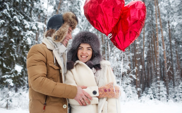 Winter verliefde paar. Jongen en meisje knuffelen in de winter Sneeuw en het sprookjesbos met ballonnen.