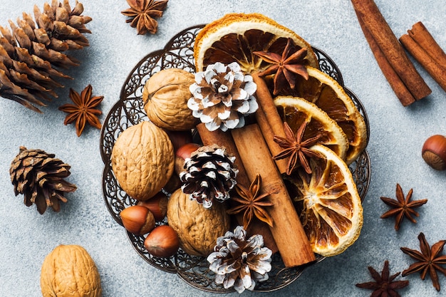 Winter voedsel ingrediënten noten kegels sinaasappels kaneel steranijs in een kom.