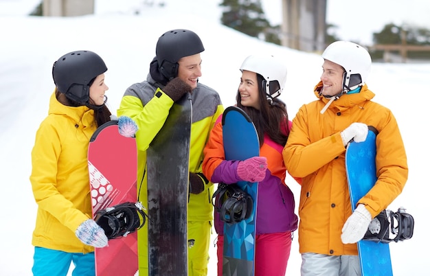 winter, vrije tijd, extreme sport, vriendschap en mensenconcept - gelukkige vrienden in helmen met snowboards die praten