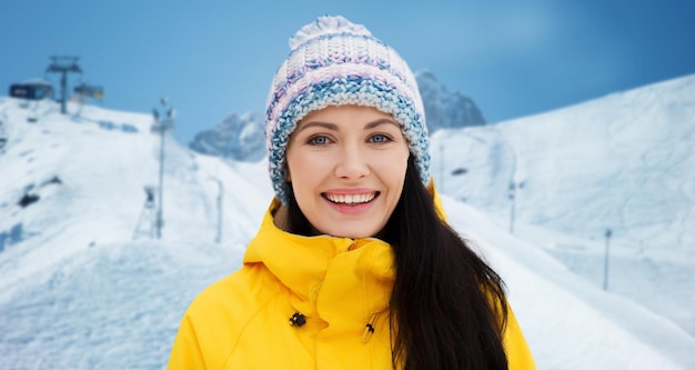 winter, vrije tijd, kleding en mensen concept - gelukkige jonge vrouw in winterkleren over skiën en bergen achtergrond