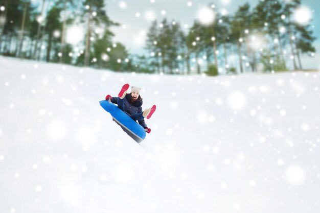 winter, vrije tijd, sport en mensen concept - gelukkig tienermeisje of vrouw die op sneeuwbuis glijdt