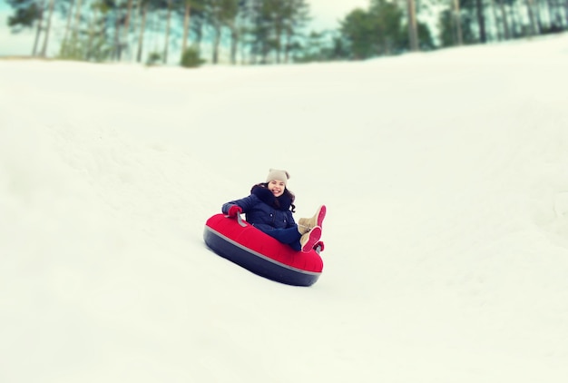 winter, vrije tijd, sport en mensen concept - gelukkig tienermeisje of vrouw die op sneeuwbuis glijdt