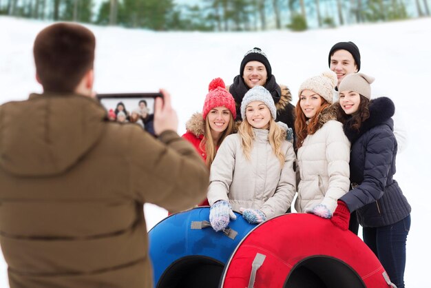 winter, vrije tijd, sport, vriendschap en mensen concept - groep lachende vrienden met sneeuwbuizen die foto's nemen door tablet pc-computer buitenshuis