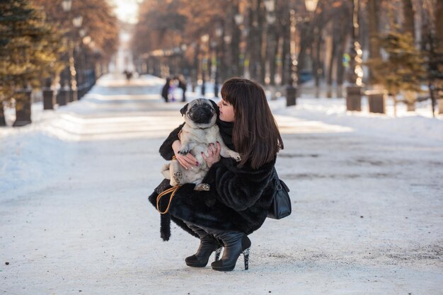 Winter walk in the park with a pug dog