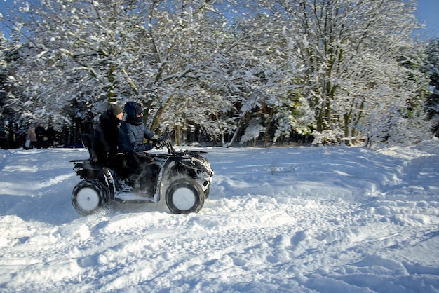 4륜 오토바이를 타고 눈 덮인 숲을 통과하는 겨울 산책