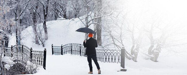 Passeggiata invernale con un ombrello. uomo con un cappotto con un ombrello, cammina sullo sfondo del paesaggio invernale, vista invernale