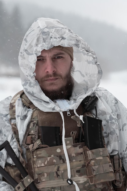 Foto guerra invernale nelle montagne artiche operazione in condizioni fredde soldato in uniforme camuffato invernale in guerra moderna esercito in un giorno di neve sul campo di battaglia della foresta con un fucile focalizzazione selettiva