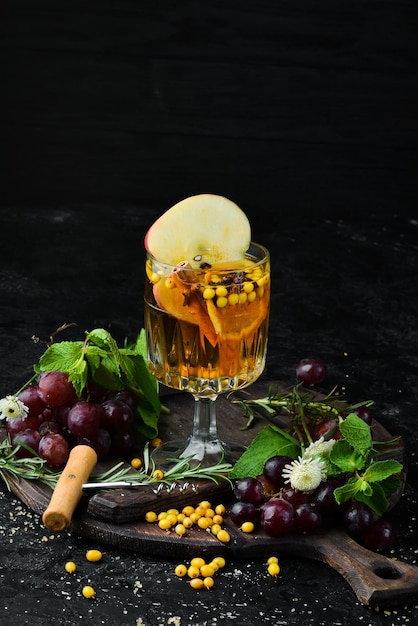 Winter warme dranken van witte wijn van appels duindoorn en kaneel In het glas Bovenaanzicht Op een zwarte achtergrond