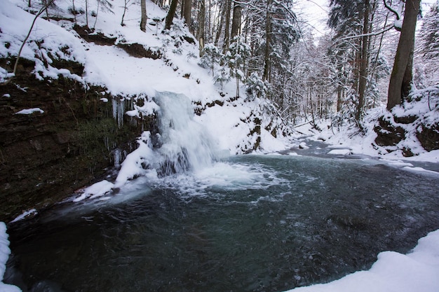 森の小さな川につららのある冬の滝美しい冬の風景