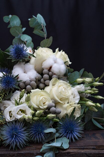 Фото Зимний свадебный букет из белых роз, хлопка и эрингиума на черном. букет невесты.