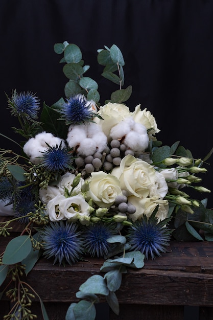 Winter wedding bouquet of white roses, cotton and eringium on a black . The bride's bouquet.