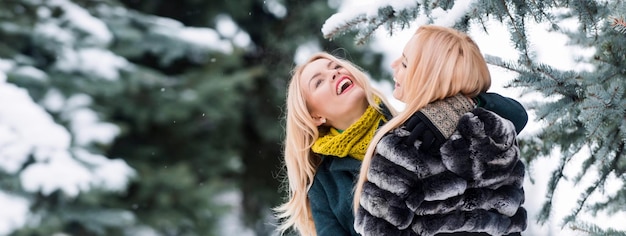 若い美しい女性 c の冬の雪に覆われた背景の屋外のポートレートで笑っている冬の女性の友人