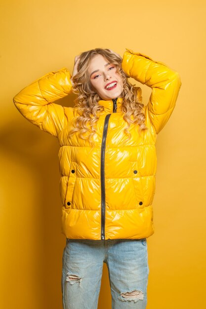 Зимняя женщина в сезонной пушистой куртке на ярко-желтом фоне
