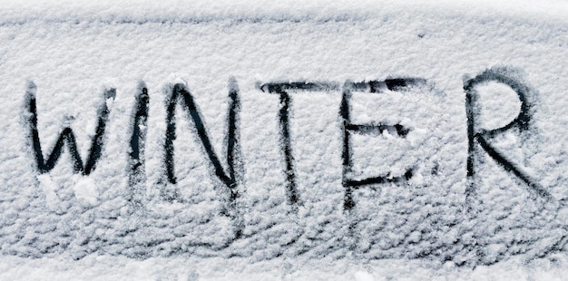 Winter written in snow on car window