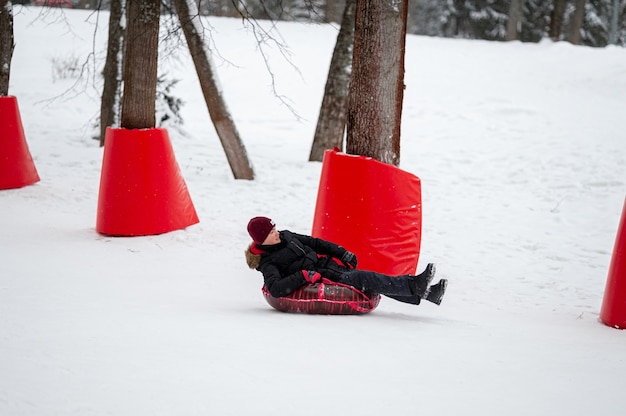 Foto winteractiviteiten tubing een tienerjongen rolt op een rode tubing op een speciaal uitgeruste veilige berghelling