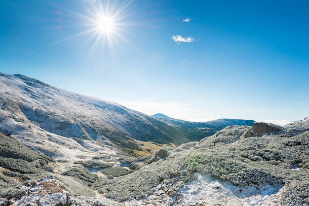 Winterbergen en zonnige groene vallei eronder. Landschap heuvels en felle zon