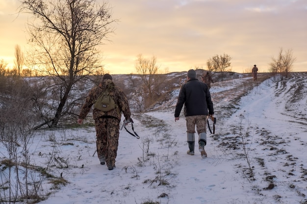 Winterjacht op hazen. Mensen met jachtgeweren op zoek naar bidden.