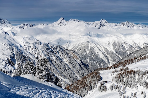 Winterlandschap; Bovenaanzicht van skigebied met blauwe lucht en ijzige pijnbomen vallende sneeuw.