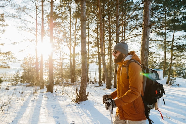 Winterlandschap een man met een rugzak en warme winterkleding in het bos die door de bergen reist
