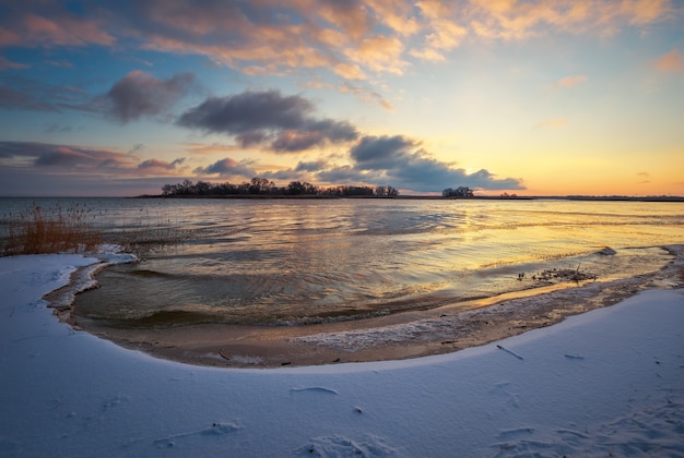 Winterlandschap met bevroren meer en avondrood. Kleurrijke oranje lucht. Samenstelling van de natuur.