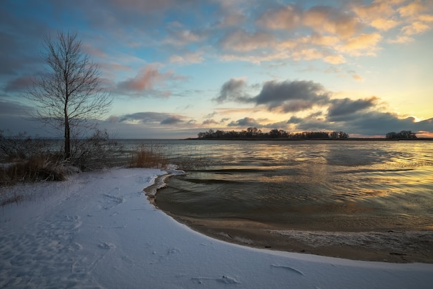 Winterlandschap met bevroren meer en avondrood. Kleurrijke oranje lucht