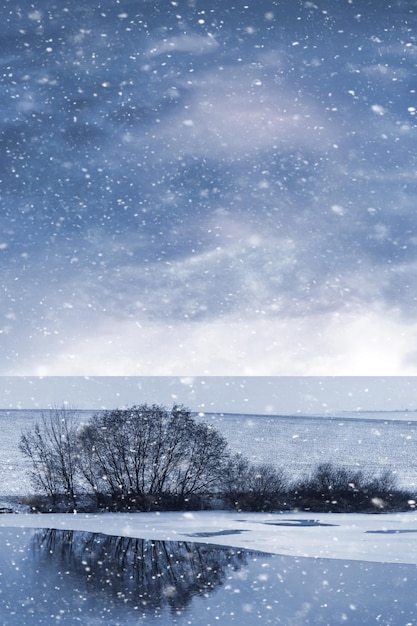 Winterlandschap met bomen aan de oever van de rivier en pittoreske lucht tijdens een sneeuwval