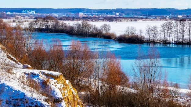 Winterlandschap met bomen en rotsen bij de rivier bij zonnig weer