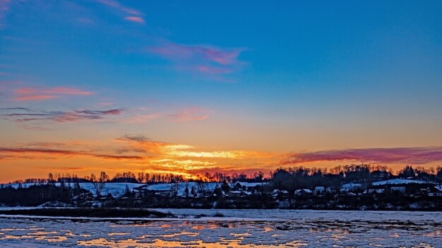 Winterlandschap Zonsondergang verlicht de rivier met drijvende ijsschotsen Getinte foto