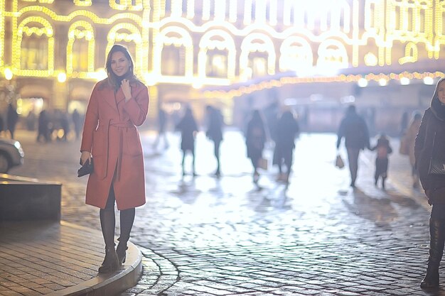 winternacht in de stadslichten / volwassen meisje in een jaswandeling in de stad, modieus stijlvol beeld van een mooi model