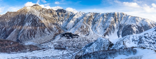 Winterpanorama van de stad Kazbegi Stepantsminda en de rotsachtige bergen van de Kaukasus in Georgië