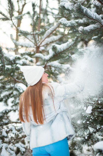 Winterportret van een meisje in het bos dat met sneeuw speelt in een warmwitte hoed Year of the Rabbit