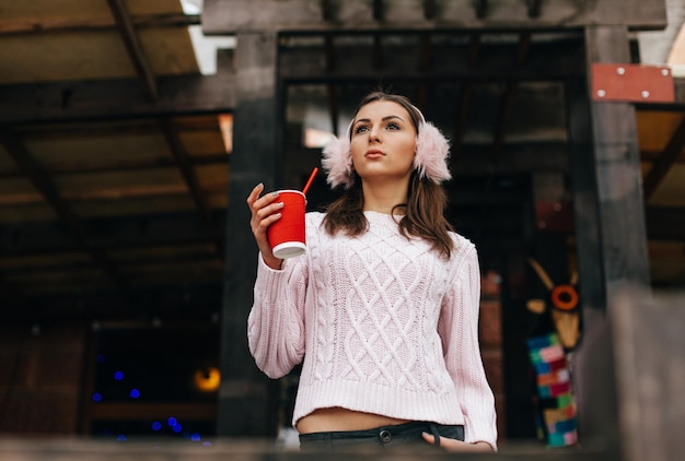 Winterportret van een mooie vrouw die een kopje koffie vasthoudt om in de winter naar buiten te gaan