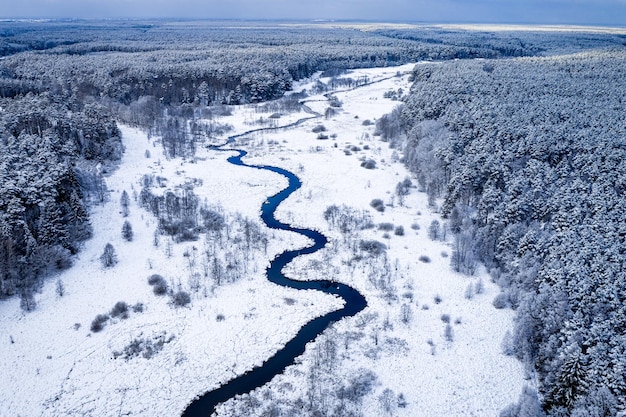 Winterrivier en besneeuwd bos Luchtfoto van de winternatuur