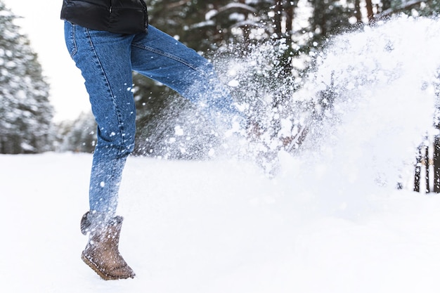 Winters buitenplezier. Vrouw die laarzen van schapenvacht draagt, schopt tegen sneeuw.